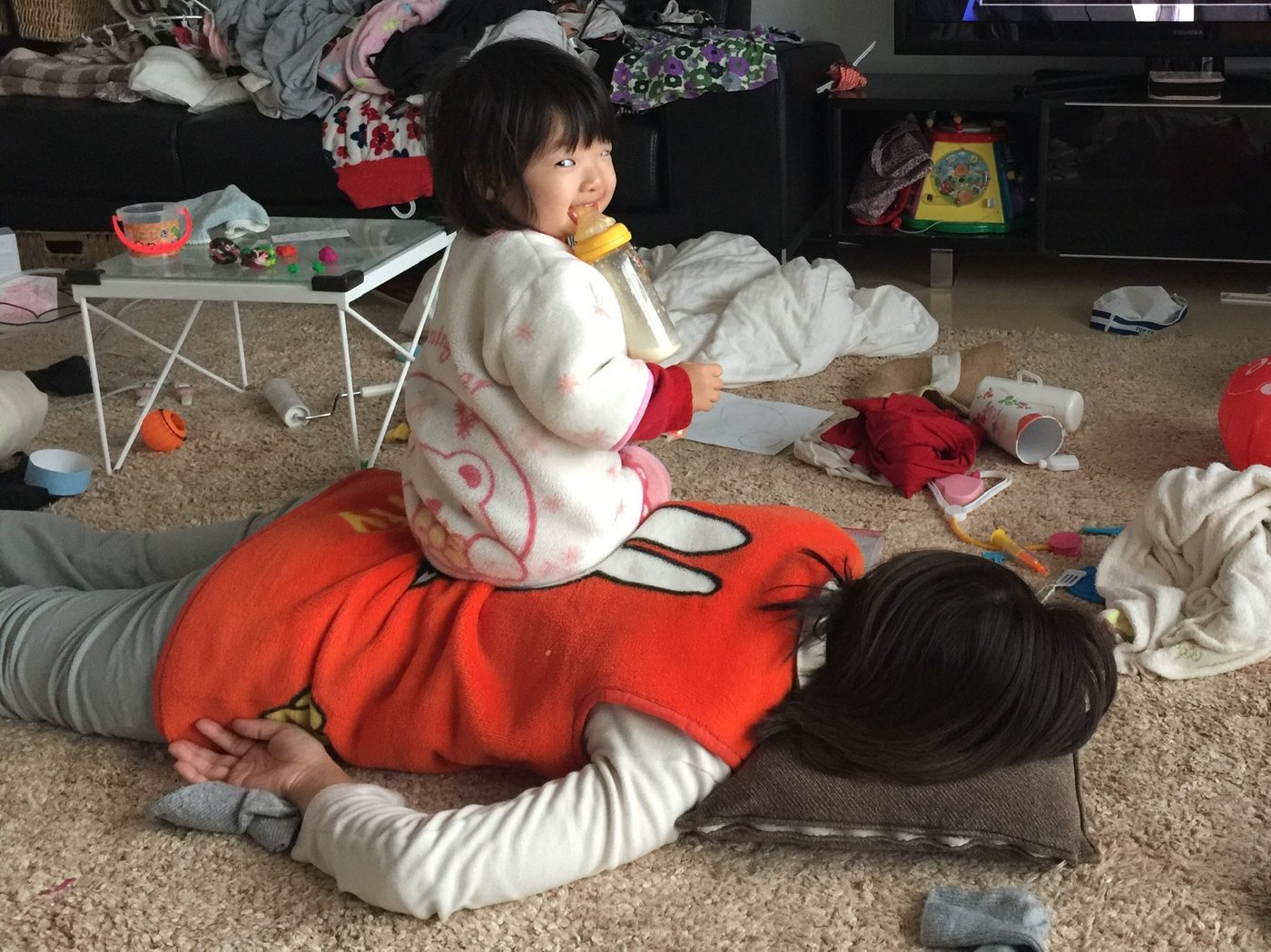 大人の背中の上に座ってミルクを持つゆいな