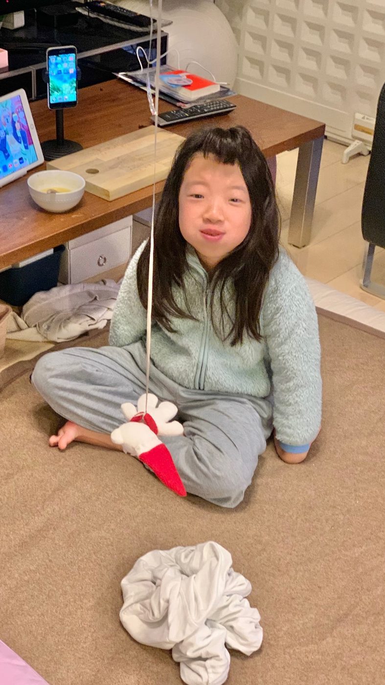 部屋で座ってこちらを見るゆいな